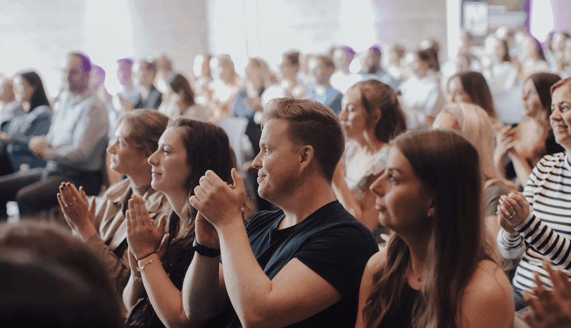 Seated SMG employees applaud at a large gathering
